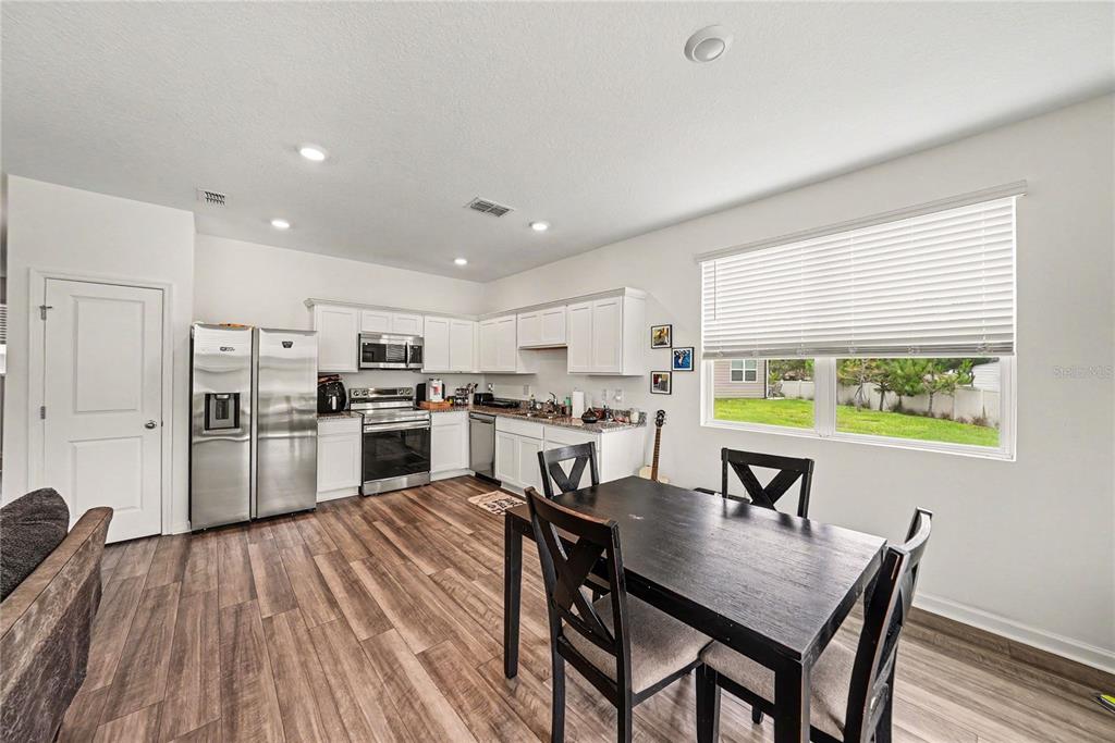 A hallway with wood-look flooring leads to a living area past a carpeted staircase — 6272 BUCKET COURT, GIBSONTON, FL