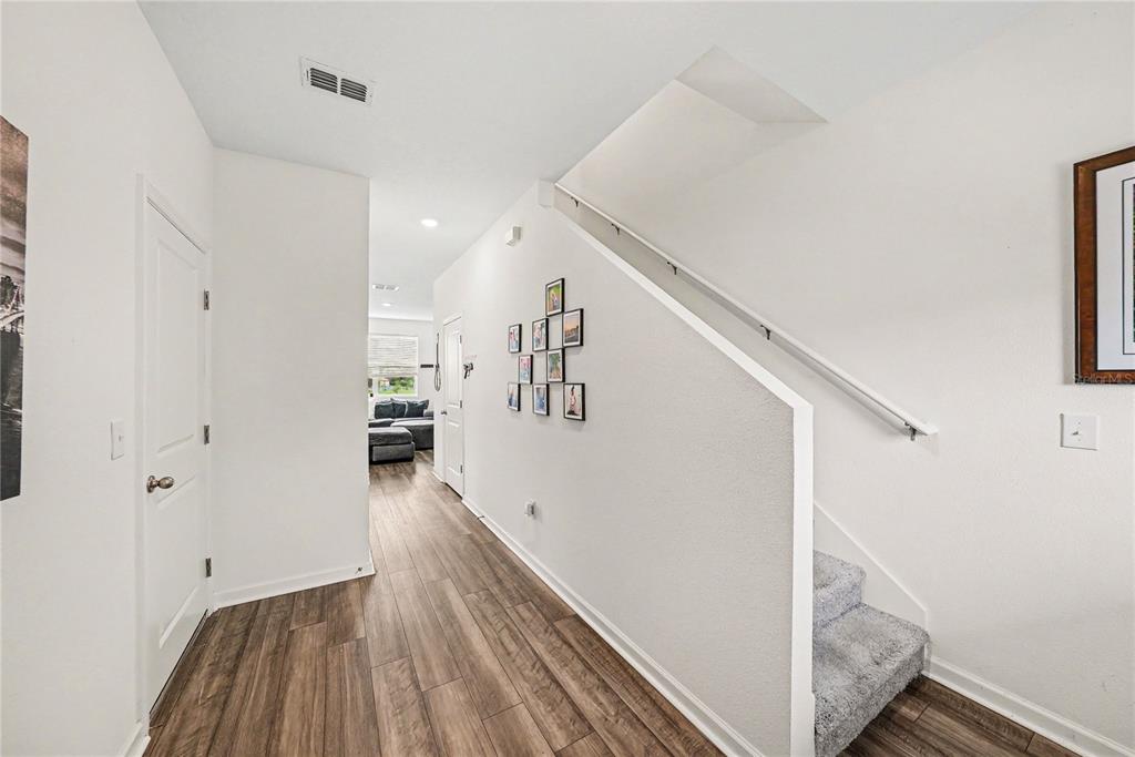 An open-concept living room and kitchen featuring a gray sectional sofa and wood flooring — 6272 BUCKET COURT, GIBSONTON, FL