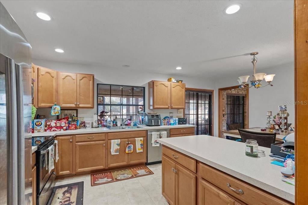 A kitchen with wood cabinets, white countertops, stainless steel appliances, and an island — 910 WHITEWOOD DRIVE, DELTONA, FL