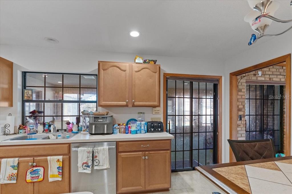 A kitchen features light wood cabinets, stainless steel appliances, and a sliding glass door — 910 WHITEWOOD DRIVE, DELTONA, FL
