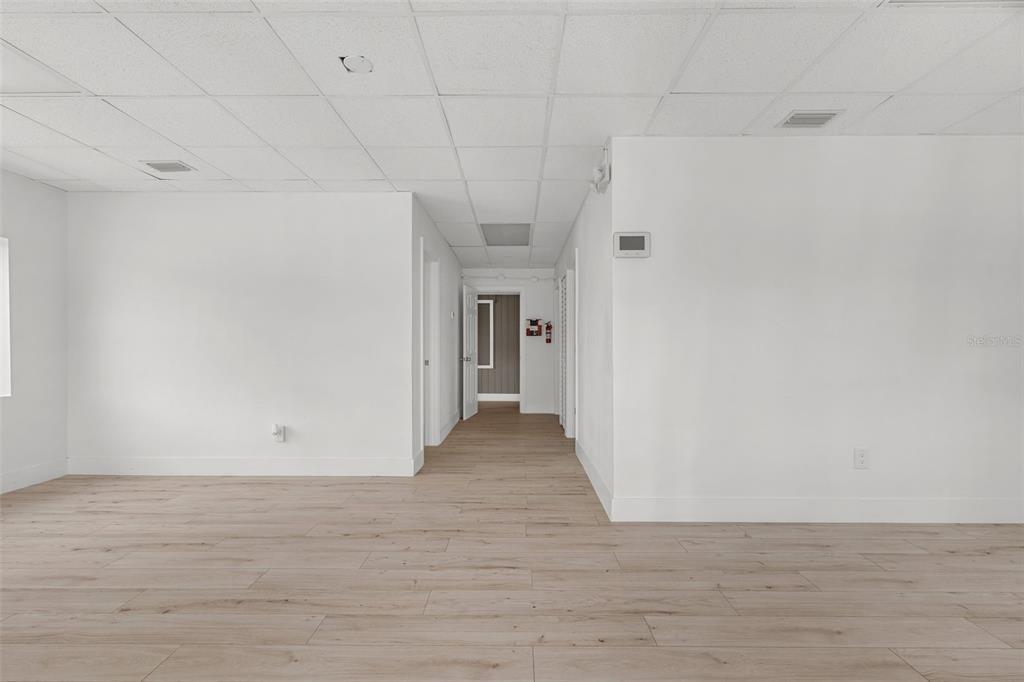 An empty room with white walls, a drop ceiling, and light-colored wood-look flooring — 10302 N NEBRASKA AVENUE, TAMPA, FL
