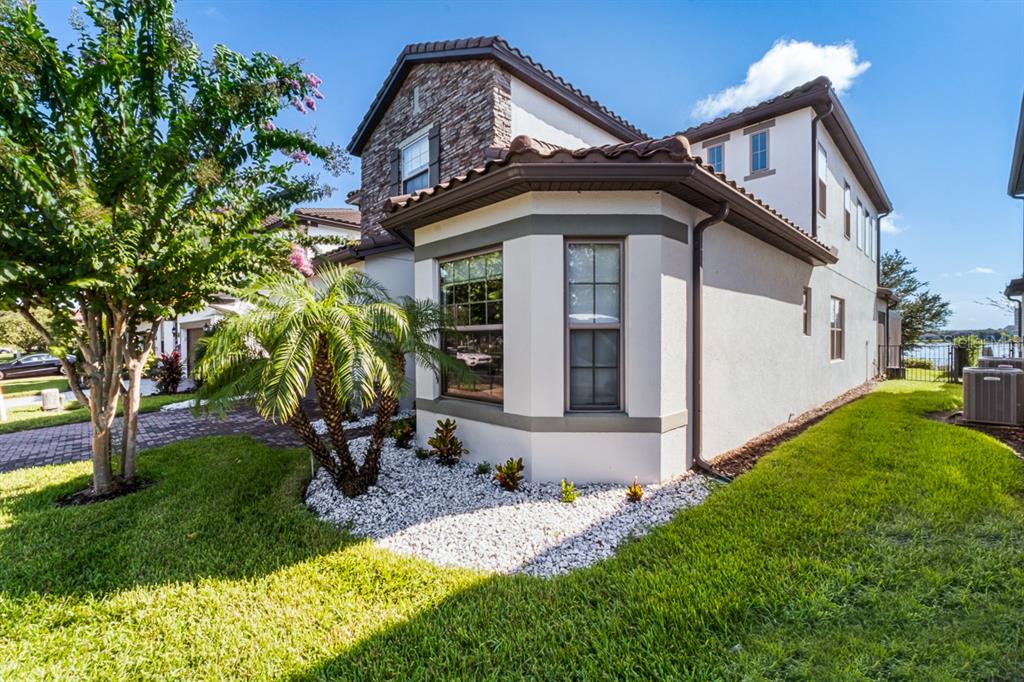 A two-story house exterior with a stone facade, bay window, palm tree, and grassy yard — 11262 LEMON LAKE BOULEVARD, ORLANDO, FL