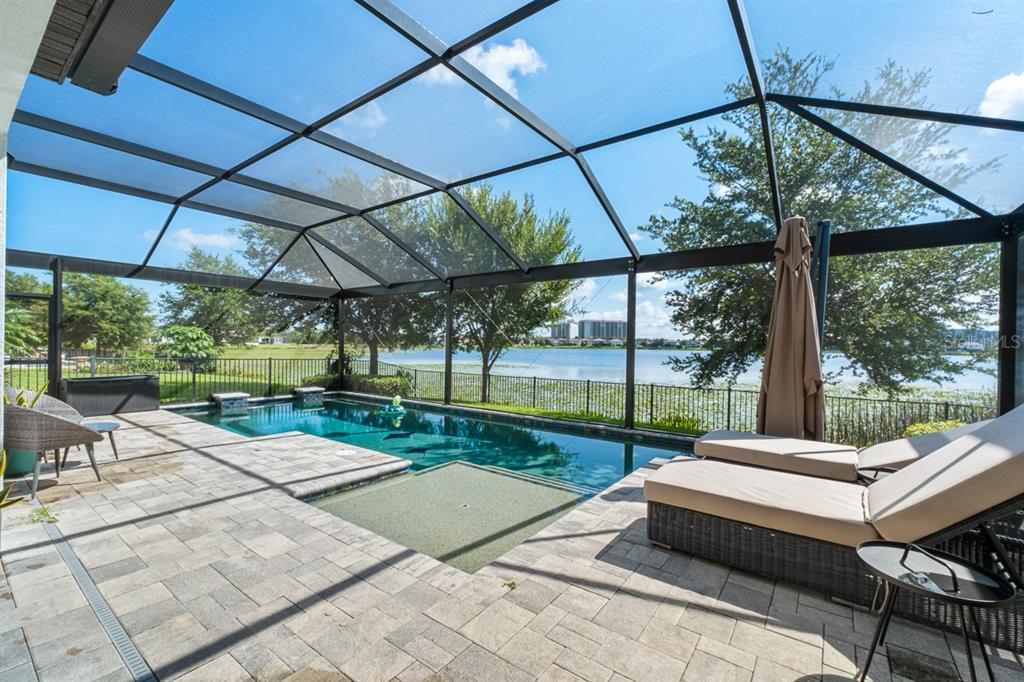 A screened-in patio features a swimming pool, lounge chairs, and a view of a lake — 11262 LEMON LAKE BOULEVARD, ORLANDO, FL