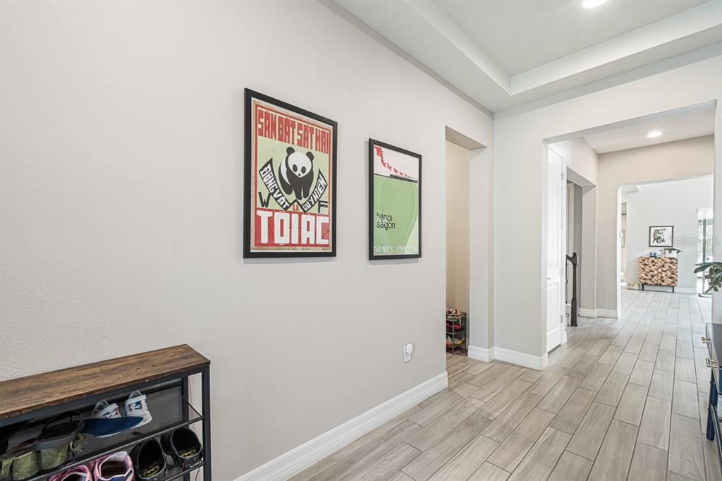 A hallway features light-colored walls, wood-look tile flooring, and two framed posters on the wall — 11262 LEMON LAKE BOULEVARD, ORLANDO, FL