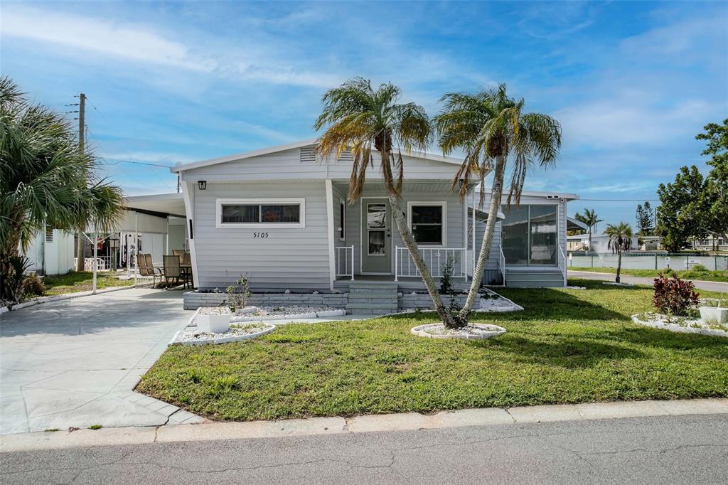 A light gray manufactured home features a front porch, two palm trees, and a driveway — 5105 8TH STREET W, BRADENTON, FL