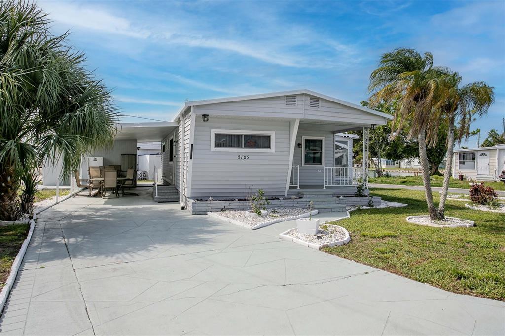 A light gray manufactured home with a carport, front porch, and concrete driveway — 5105 8TH STREET W, BRADENTON, FL