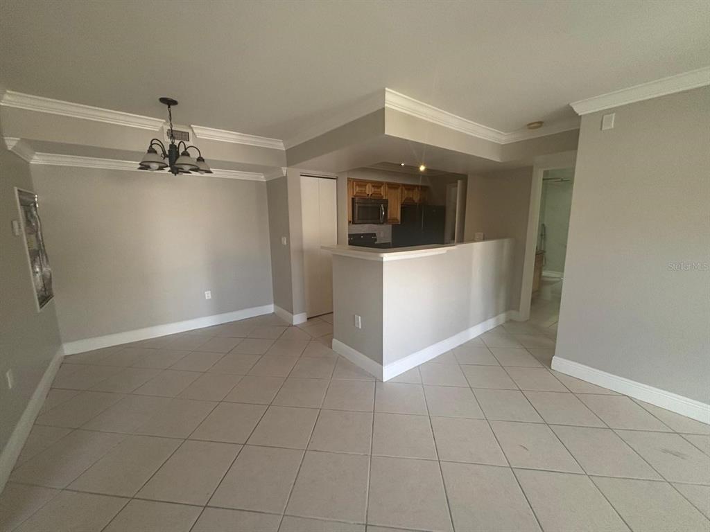 A dining area with a chandelier leads to a kitchen with a breakfast bar — 3038 PARKWAY BOULEVARD UNIT 208, KISSIMMEE, FL