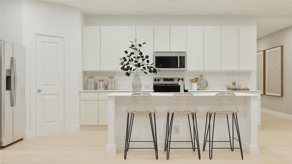 A modern kitchen features white cabinetry, a central island with three stools, and stainless appliances — 3058 GRANITE RIDGE AVENUE, MINNEOLA, FL