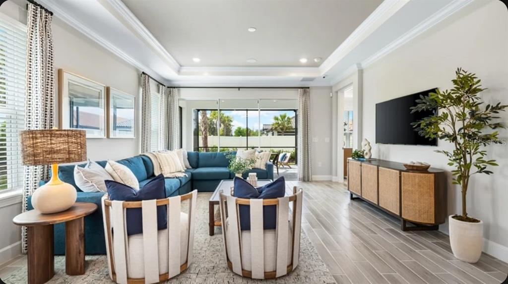 A living room features a blue sectional sofa, two accent chairs, and a media console — 4305 ROSATTI ROAD, WESLEY CHAPEL, FL
