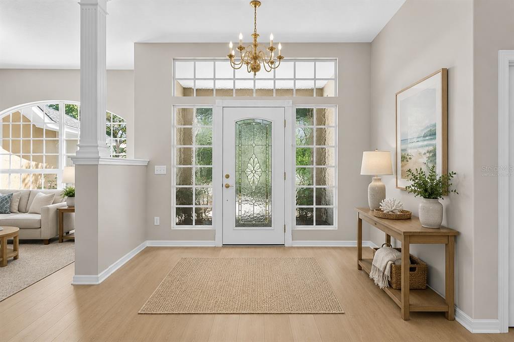 A bright entryway features light wood flooring, a decorative front door, and a wooden console table — 22 IBIS COURT N, PALM COAST, FL