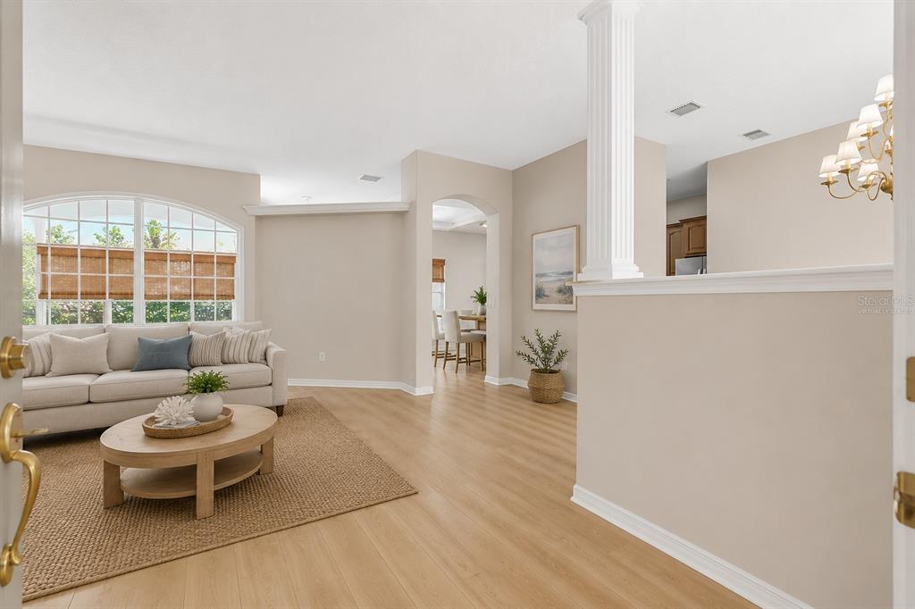 A living room with light wood flooring, a beige sofa, and an arched entryway — 22 IBIS COURT N, PALM COAST, FL