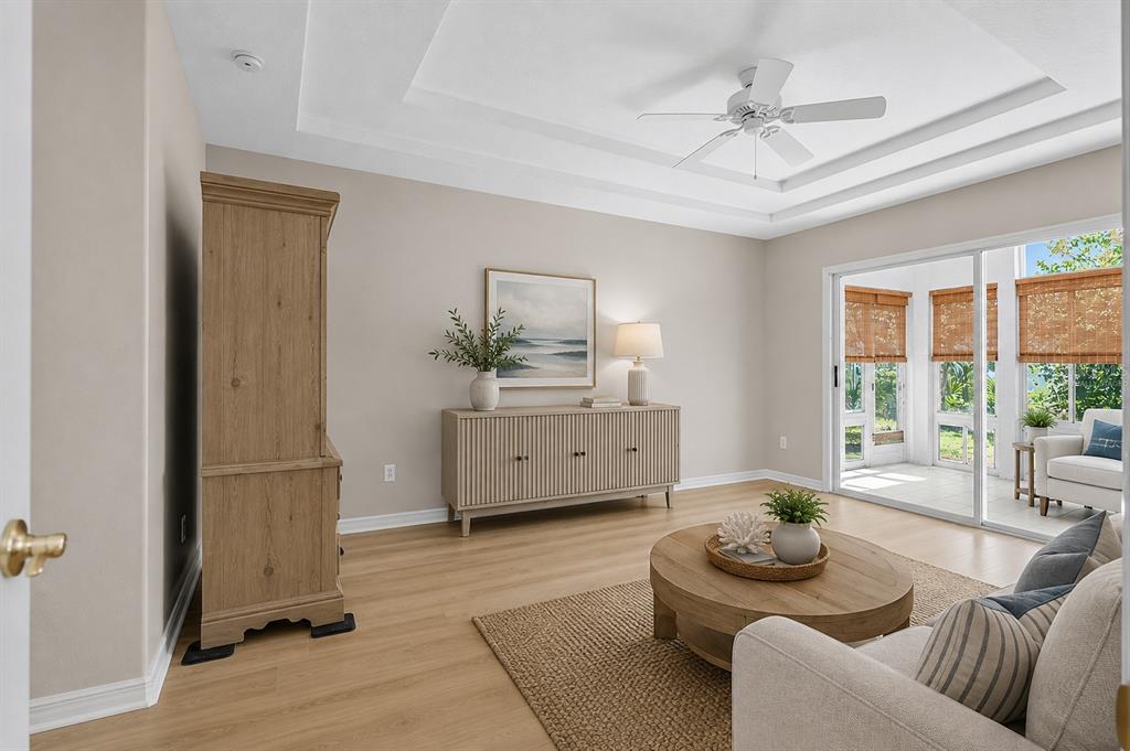 A living room with light wood flooring, a tray ceiling, and sliding doors to a patio — 22 IBIS COURT N, PALM COAST, FL
