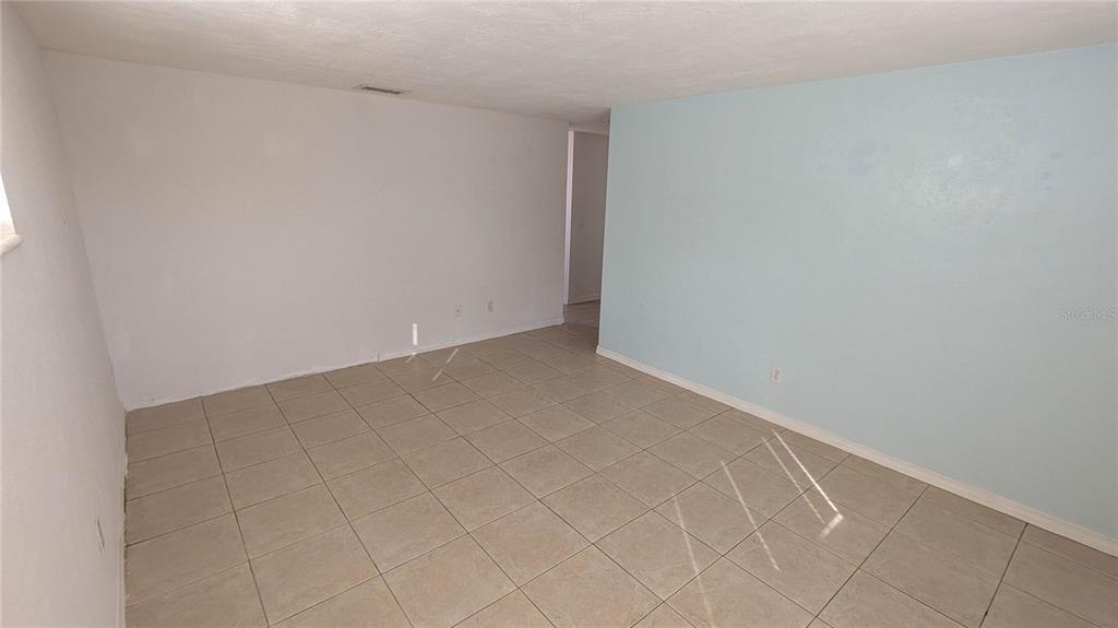 An empty room with light-colored tile flooring and one light blue accent wall — 11301 110TH TERRACE, LARGO, FL