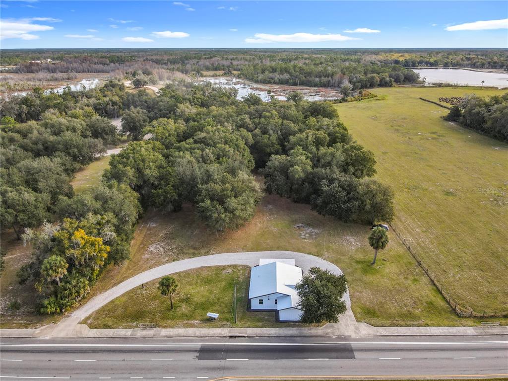 An aerial view shows a white house with a metal roof on a large lot — 379 N SR 415, OSTEEN, FL
