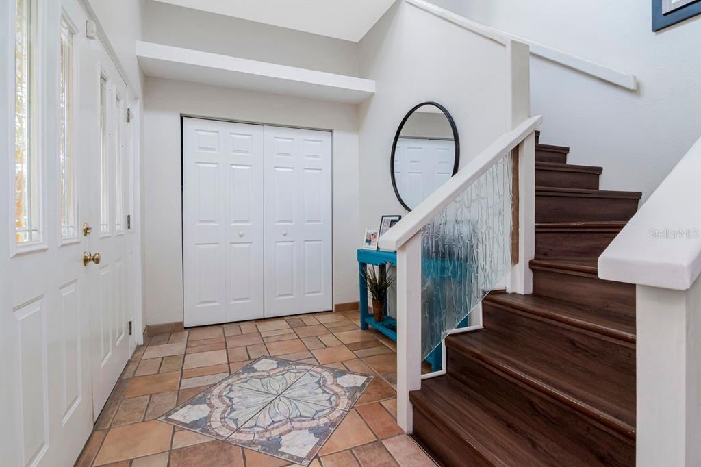 A staircase with wood treads and glass panels leads up from a tiled dining area — 10532 67TH AVENUE, SEMINOLE, FL