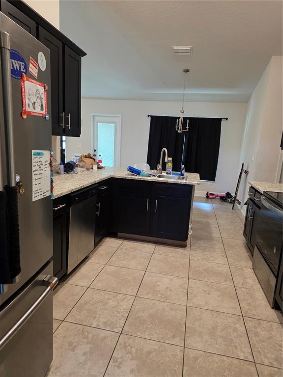 A kitchen features dark cabinets, granite countertops, stainless steel appliances, and light-colored tile flooring — 9 CEDAR RUN, OCALA, FL