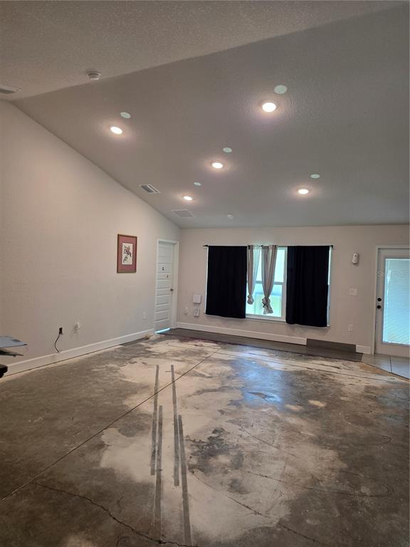 An unfinished room with a concrete floor, recessed lighting, and a vaulted ceiling — 9 CEDAR RUN, OCALA, FL