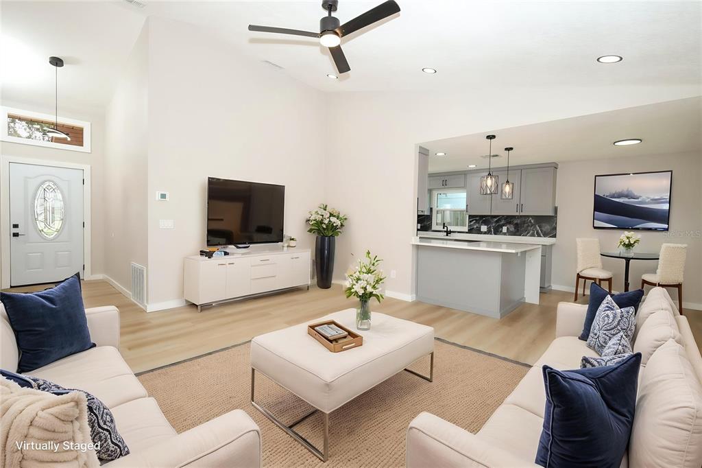 A living room with light wood floors, a white sofa, and an open kitchen area — 761 ROBINHOOD DRIVE, MAITLAND, FL