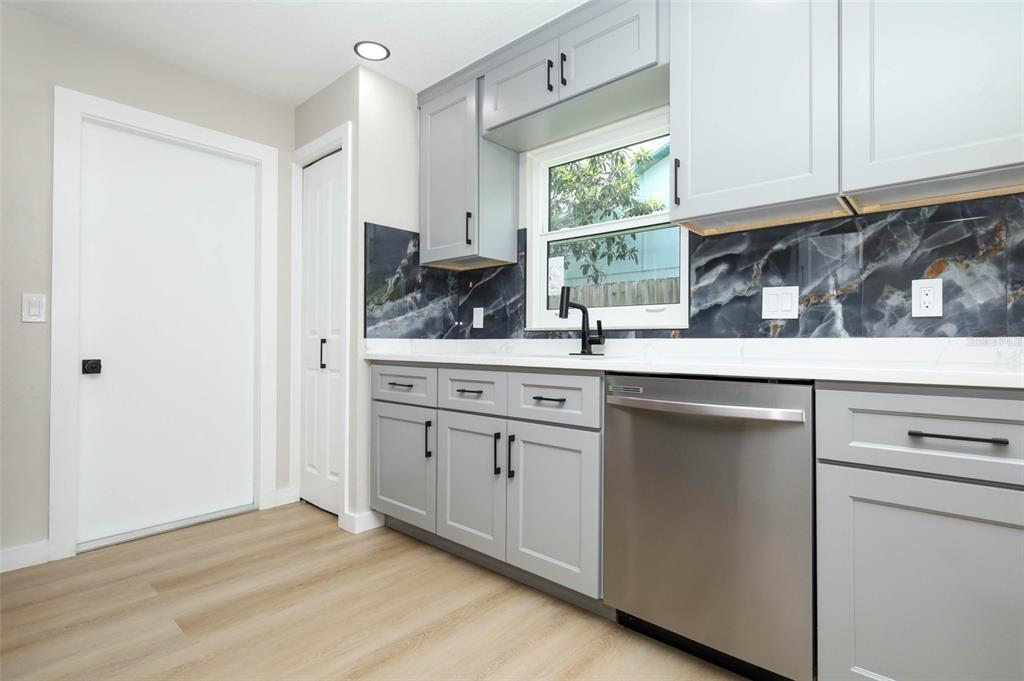 A kitchen features gray cabinets, a dark marble-patterned backsplash, stainless steel appliances, and light flooring — 761 ROBINHOOD DRIVE, MAITLAND, FL