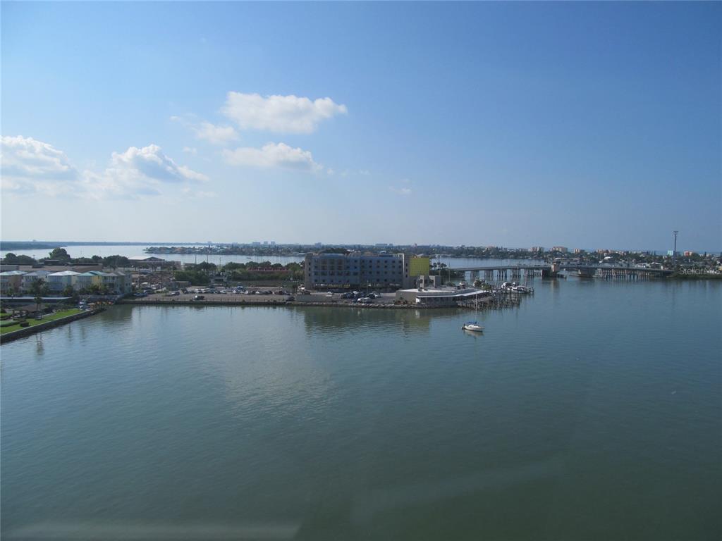 An elevated view of a waterfront area with a hotel, bridge, and parked cars — 4775 COVE CIRCLE UNIT 1202, MADEIRA BEACH, FL