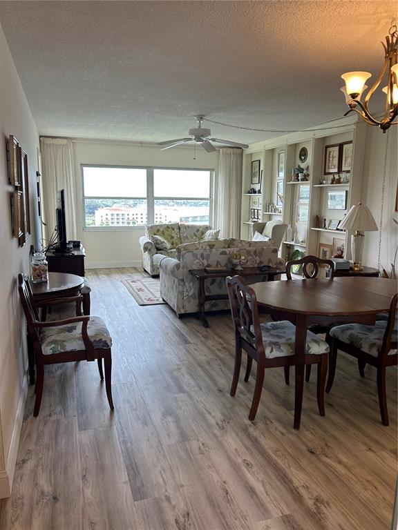 A living and dining area features wood-look flooring, floral furniture, and a large window view — 4775 COVE CIRCLE UNIT 1202, MADEIRA BEACH, FL