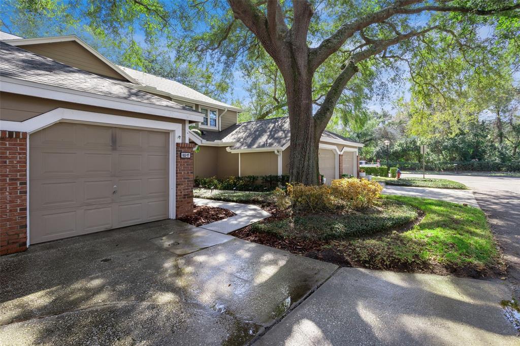 A tan townhouse with a brick-accented garage and a large tree in the front yard — 683 POST OAK CIRCLE UNIT 117, ALTAMONTE SPRINGS, FL