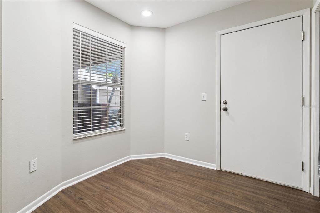 An empty room with light gray walls, wood-look flooring, a window with blinds, and a door — 683 POST OAK CIRCLE UNIT 117, ALTAMONTE SPRINGS, FL