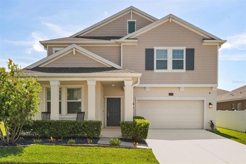 A two-story suburban house with beige siding, a front porch, and a two-car garage — 1919 PERCH HAMMOCK LOOP, GROVELAND, FL