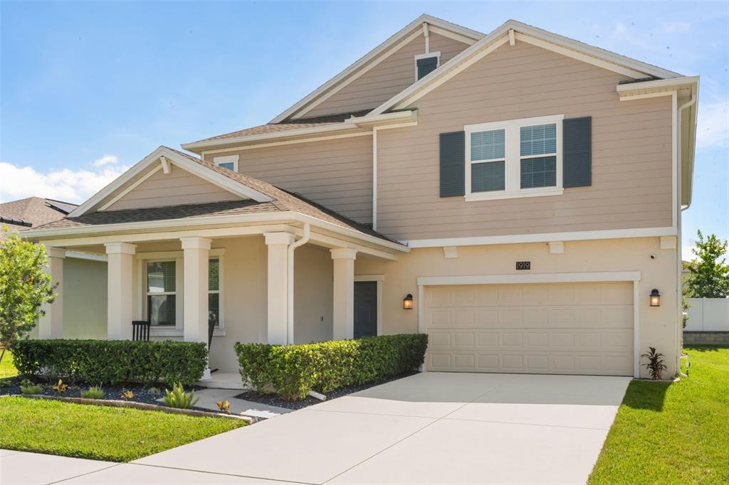 A two-story suburban house with beige siding, a front porch, and a two-car garage — 1919 PERCH HAMMOCK LOOP, GROVELAND, FL