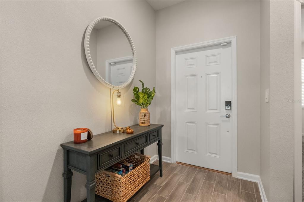 An entryway features a gray console table, a round mirror, and a white front door — 1919 PERCH HAMMOCK LOOP, GROVELAND, FL