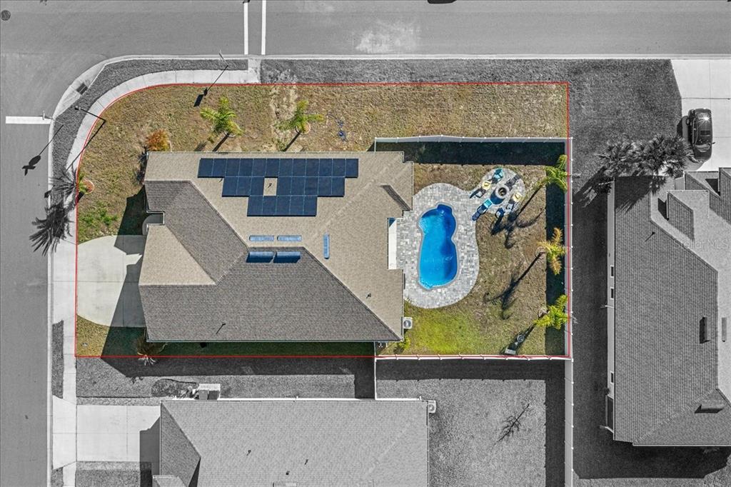 An aerial view shows a house with solar panels, a backyard pool, and a fenced yard — 23 GYPSUM PLACE, ST AUGUSTINE, FL