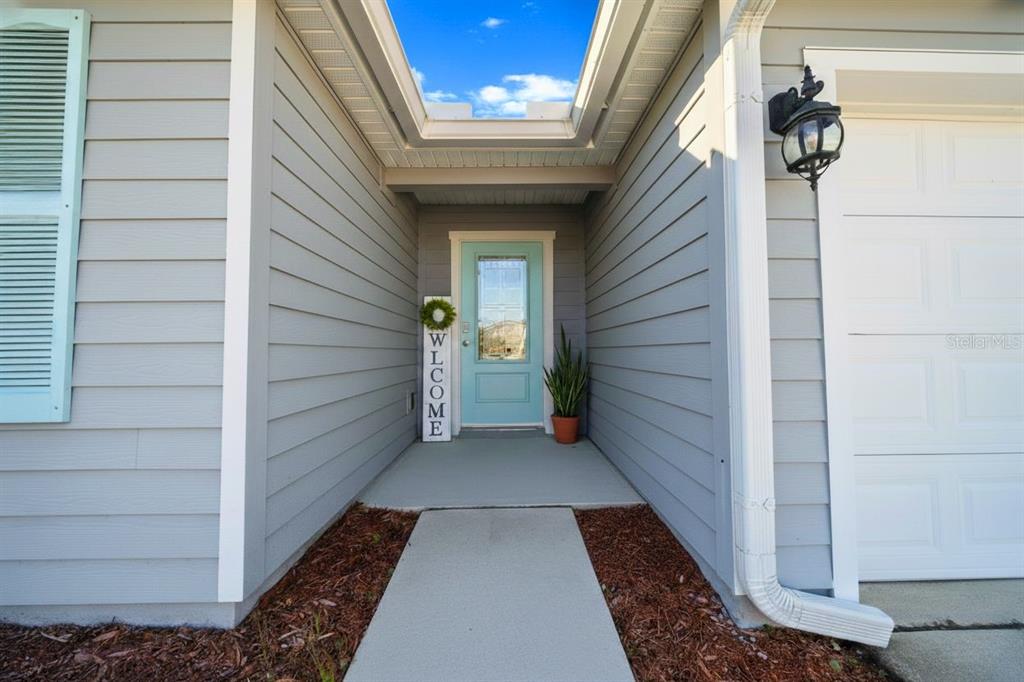 A light blue front door with a welcome sign sits under a recessed entryway — 23 GYPSUM PLACE, ST AUGUSTINE, FL