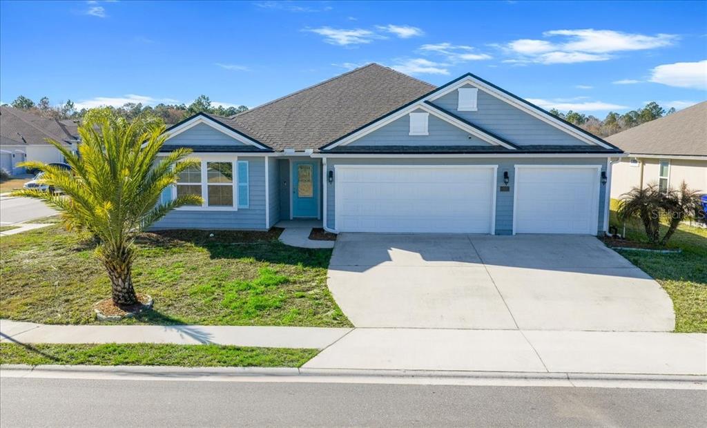 A single-story blue house with a three-car garage and a palm tree in the yard — 23 GYPSUM PLACE, ST AUGUSTINE, FL