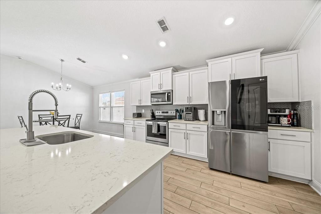 A modern kitchen features white cabinets, stainless steel appliances, and a large quartz-topped island — 23 GYPSUM PLACE, ST AUGUSTINE, FL