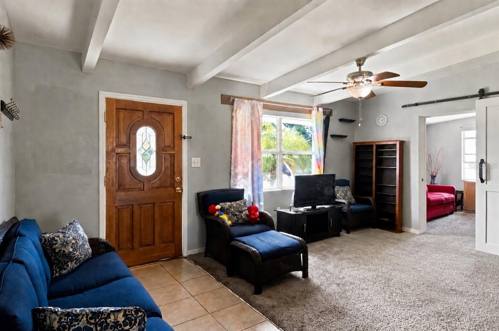 A living room features a blue sofa, a wicker chair with ottoman, and a wooden door — 1311 WINDSOR WAY, TAMPA, FL