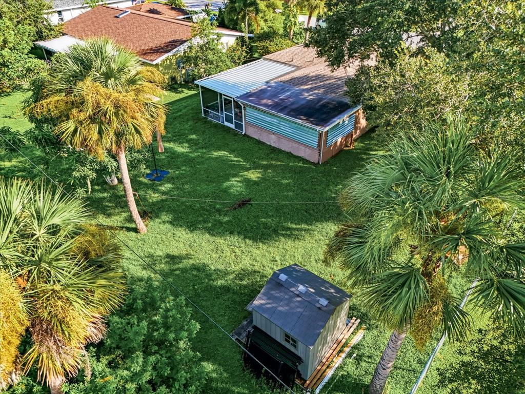 An aerial view of a backyard featuring a house, a shed, and several palm trees — 2403 DUKE LN, PORT CHARLOTTE, FL