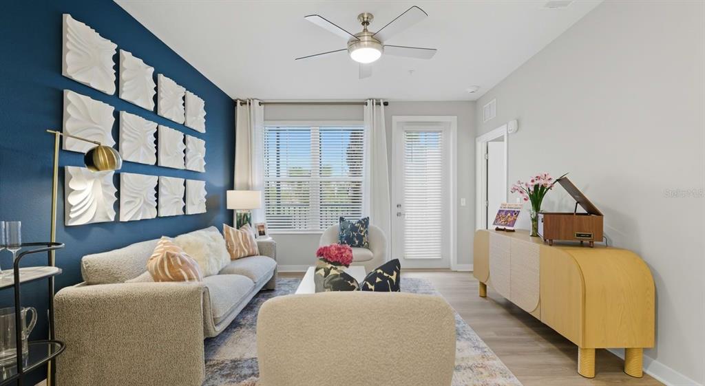A living room features a blue accent wall with white wall art and a sofa — 32475 SUGARPLUM LOOP UNIT 4201, WESLEY CHAPEL, FL