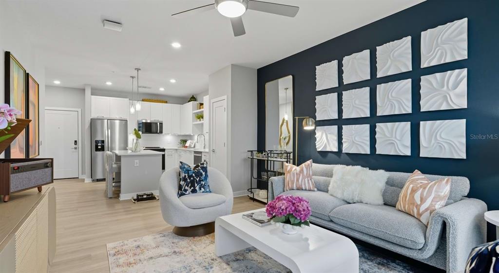 A modern living room features a dark blue accent wall with white textured square art — 32475 SUGARPLUM LOOP UNIT 4201, WESLEY CHAPEL, FL