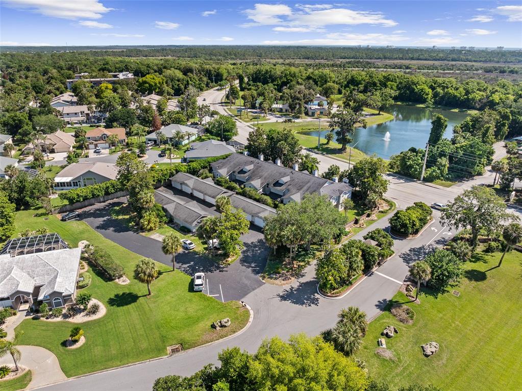 An aerial view shows a residential complex with a parking lot and a nearby pond — 596 N NOVA ROAD UNIT 308, ORMOND BEACH, FL