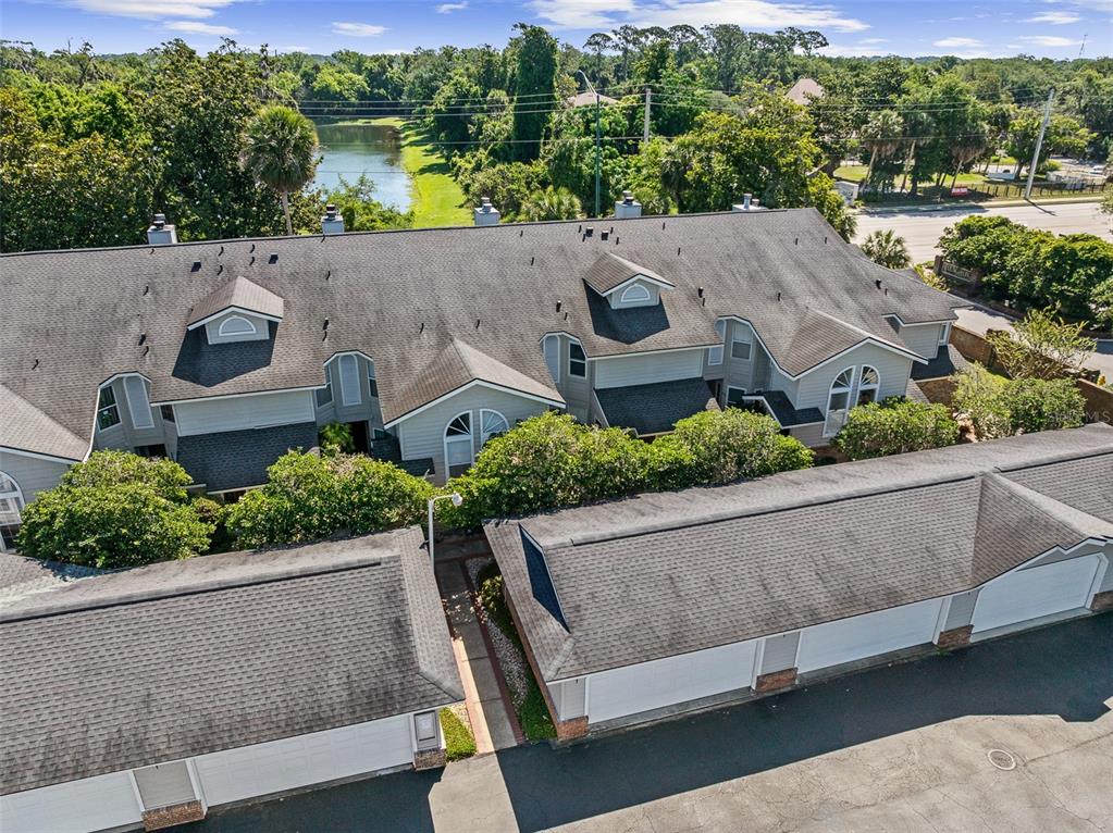 An aerial view shows a multi-unit residential building with attached garages and a nearby pond — 596 N NOVA ROAD UNIT 308, ORMOND BEACH, FL