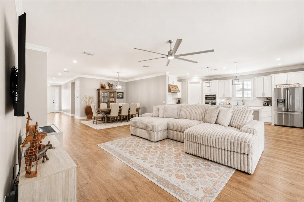 An open-concept dining and living area features wood flooring, a rectangular table, and sliding doors — 3870 BOWFIN TRAIL, KISSIMMEE, FL