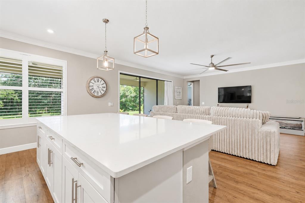 A living room with a large sectional sofa, wood flooring, and a wall-mounted television — 3870 BOWFIN TRAIL, KISSIMMEE, FL