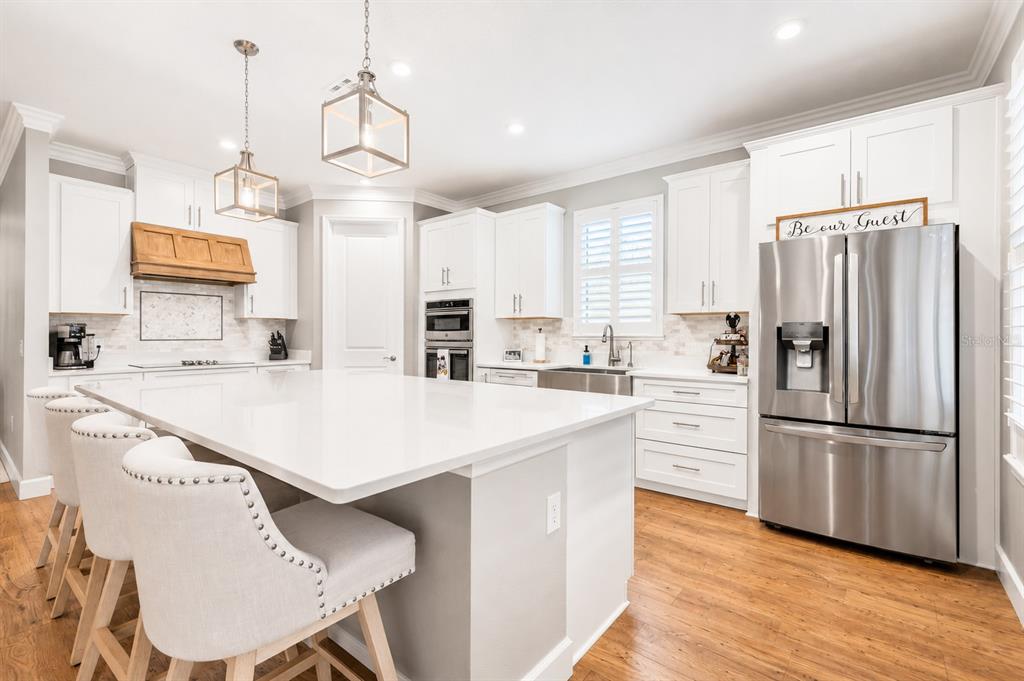 An open-concept living room and dining area with light wood flooring and a sectional sofa — 3870 BOWFIN TRAIL, KISSIMMEE, FL