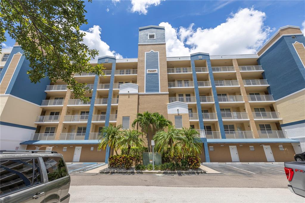 A multi-story apartment building with balconies, blue and tan exterior walls, and palm trees — 960 STARKEY ROAD UNIT 2202, LARGO, FL