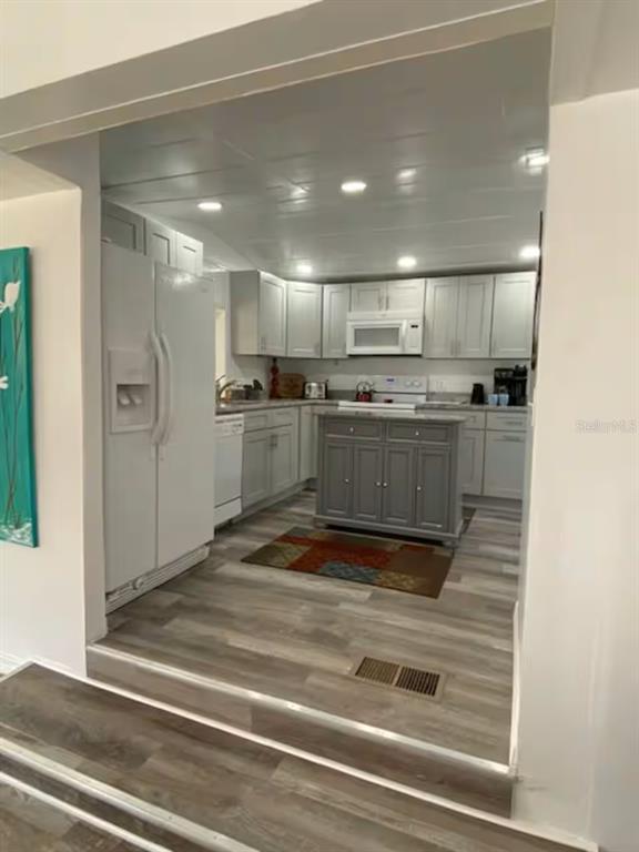 A kitchen with light gray cabinets, a dark gray island, and white appliances — 5247 ALPACA DRIVE, WEEKI WACHEE, FL