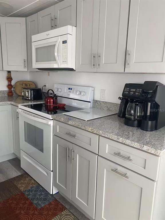 A kitchen features light gray cabinets, white appliances, and speckled granite countertops — 5247 ALPACA DRIVE, WEEKI WACHEE, FL
