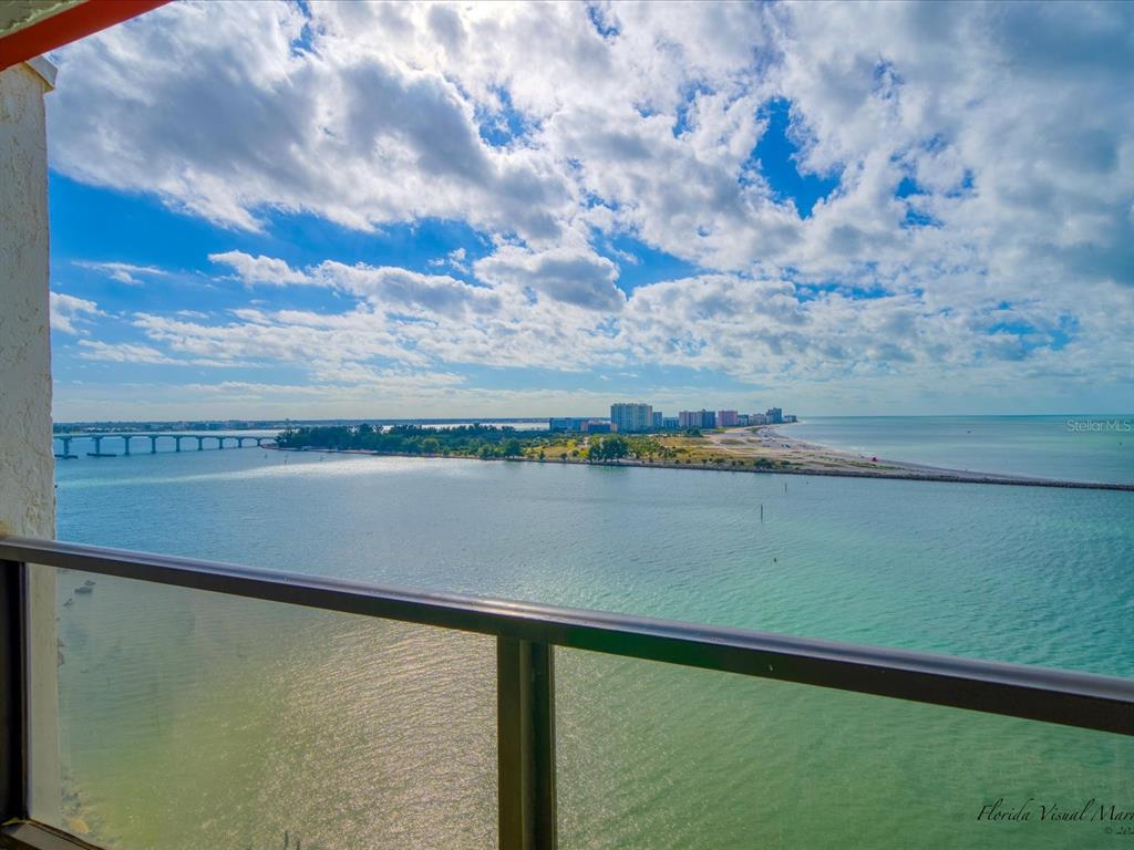 A balcony view overlooking a bay, a bridge, and a distant coastline under a cloudy sky — 450 GULFVIEW BOULEVARD S UNIT 1708, CLEARWATER, FL