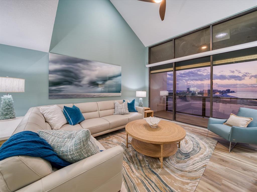 A living room with a sectional sofa, round coffee table, and large windows overlooking water — 450 GULFVIEW BOULEVARD S UNIT 1708, CLEARWATER, FL