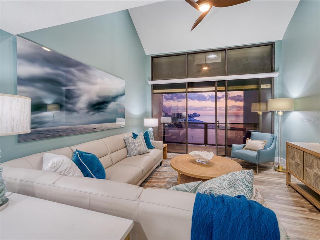 A living room features a vaulted ceiling, a large sectional sofa, and a balcony view — 450 GULFVIEW BOULEVARD S UNIT 1708, CLEARWATER, FL