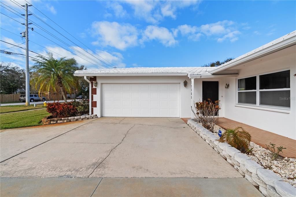 A white house exterior features a two-car garage, a concrete driveway, and a small porch — 13565 86TH AVENUE, SEMINOLE, FL
